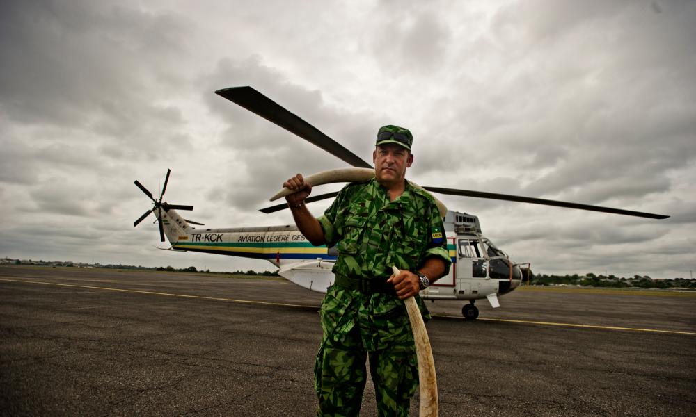 Man with tusks in front of a helicopter