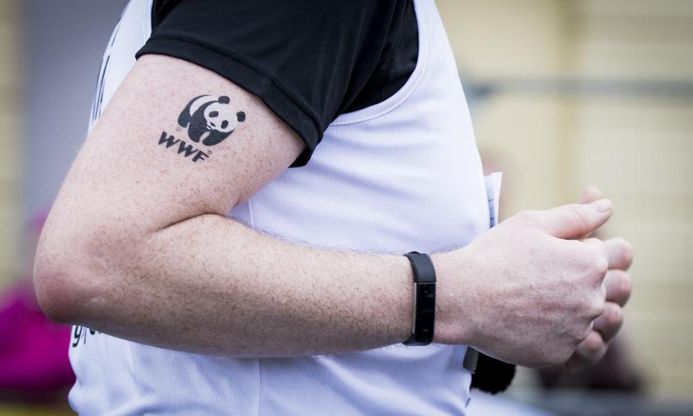 A close up on a runner's arm with a WWF tattoo on his bicep