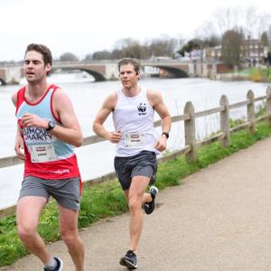 Two white males running alongside the river Thames in winter