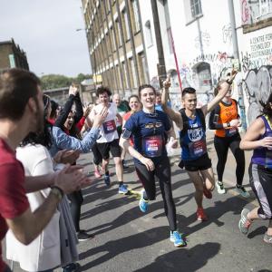 Runners are being cheered on as they go past a street in Hackney with graffitis