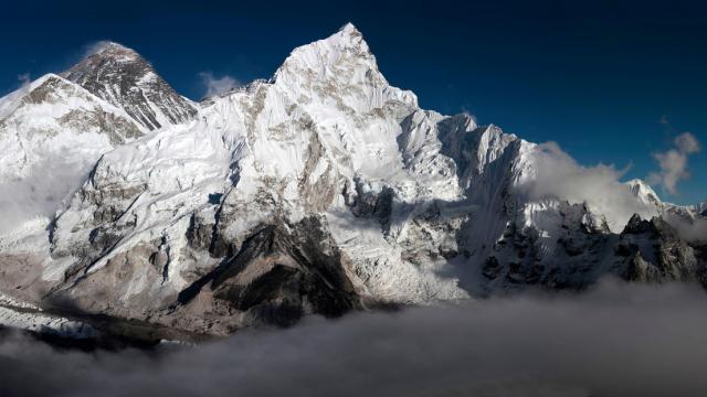 Mount Everest in the Everest Range of the Himalayas in Nepal. Everest is the peak to the left of the picture with snow blowing off its top.