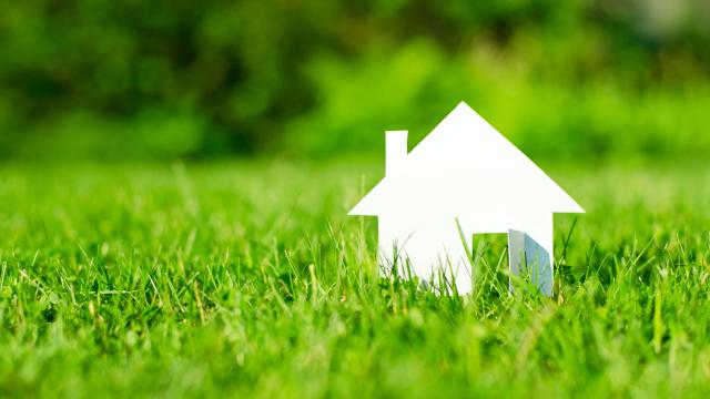 House in green field representing financial investment in renewable energy and sustainable development.