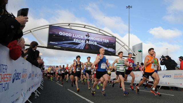Runners in the Manchester Marathon under good luck sign
