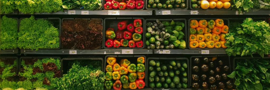 Photo of vegetables on shelves for sale at a market or supermarket including lettuce, red, yellow and green peppers and cucumbers