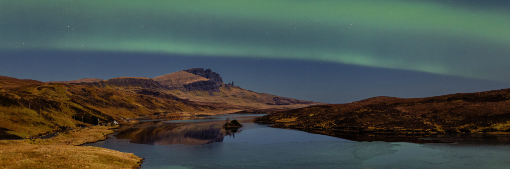 Green hues dancing across the night sky, over the Isle of Skye. The Old Man of Storr can be seen in the distance.