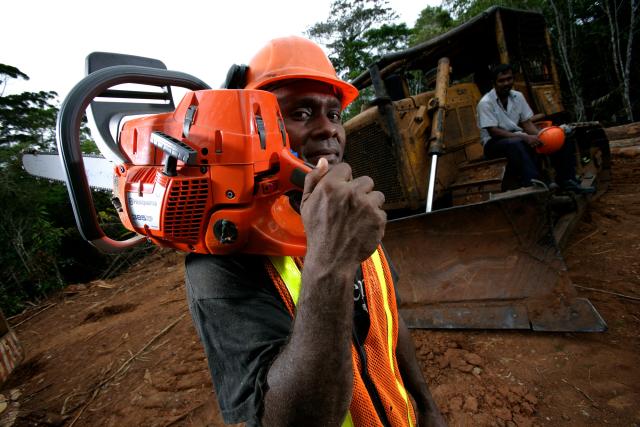 A portrait of a logger holding a chainsaw