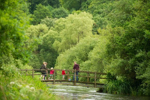 A family cross a bridge, River Itchen, Hampshire, UK