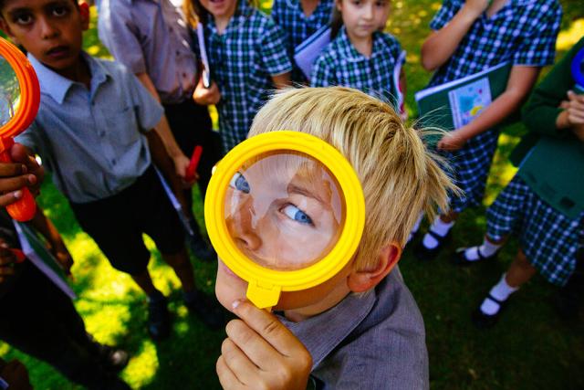 A boy looks through a magnifying glass. Him and his schoolmates have been working with WWF to learn more about nature in their school