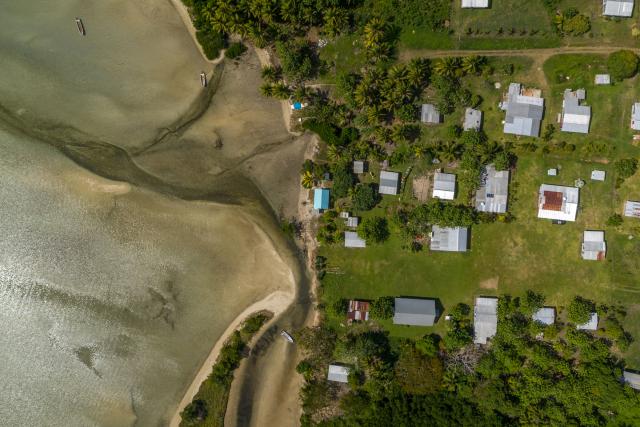 Aerial shot of the tide coming in at Raviravi village. During king tide (highest tide of the month during full moon) the seawater regularly floods the houses closest to the beach. Vanua Levu, Fiji. 