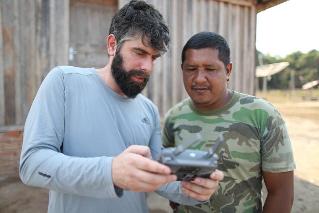  The WWF-Brasil Conservation Analyst Henrique Santiago teaches the Jahui leader, Nilcélio Jahui, how to operate a drone. Scene registered at the Jahui village, in the city of Manicoré.