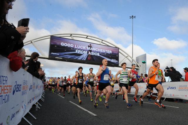 Runners in the Manchester Marathon under good luck sign