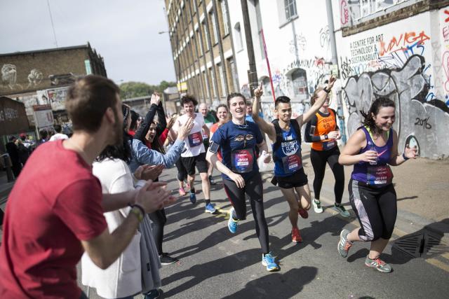 Runners are being cheered on as they go past a street in Hackney with graffitis