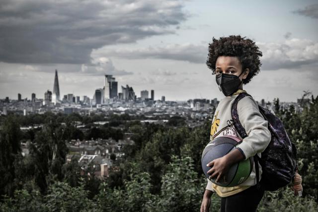 Afrika, 8, holds a ball and wears a mask to protect against air pollution. Dawson Heights, south east London.