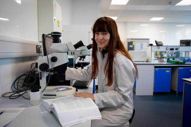 Portrait of Issy Inman using a microscope to study marine life connected with seagrass. Swansea University, Swansea, Wales, UK.