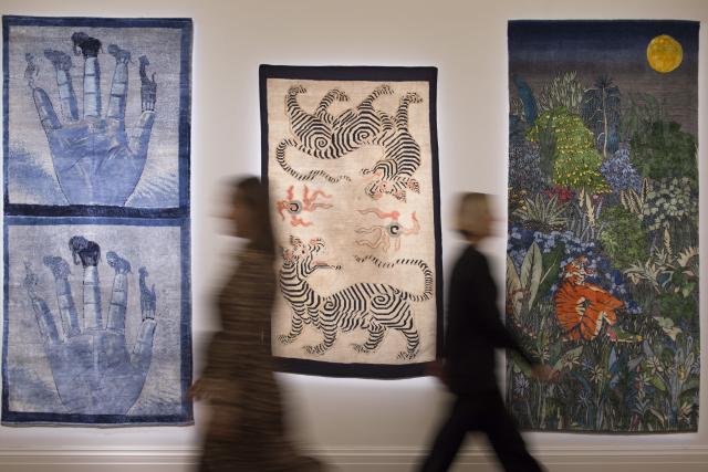 Blurred people in motion in front of three artworks in a gallery