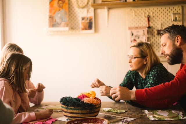 A community textile workshop supported by a WWF Cymru grant. The image shows two parents and two children sitting across from each other.