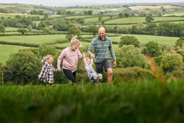 The family at Rest Farm, both parents and two children, walk through the field.