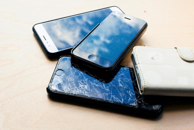 Four unused or broken mobile phones in pile 
