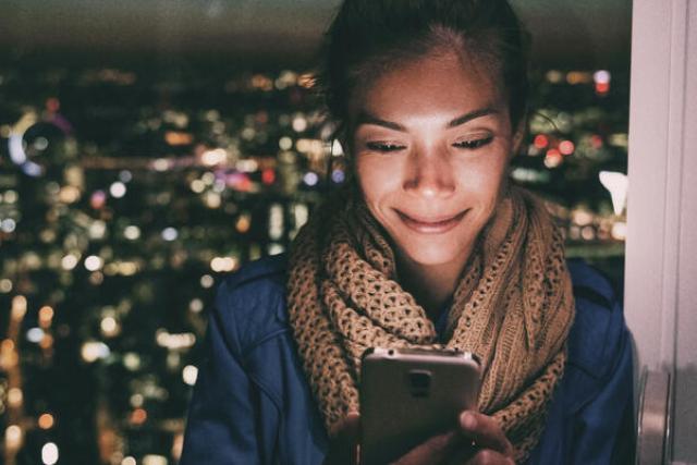 Person looking at phone with city backdrop
