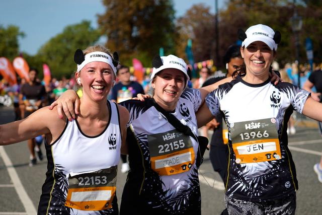 Three WWF runners smiling and waving as they take part in the Royal Parks Half Marathon