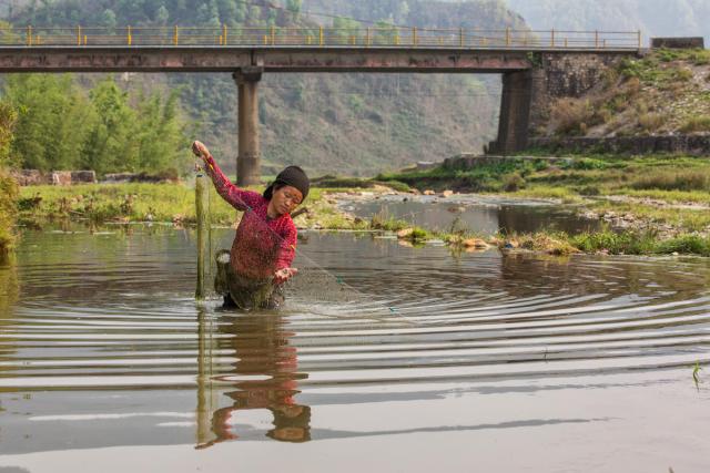 Maya Tapa fishing in a river near Simjung, Nepal.
