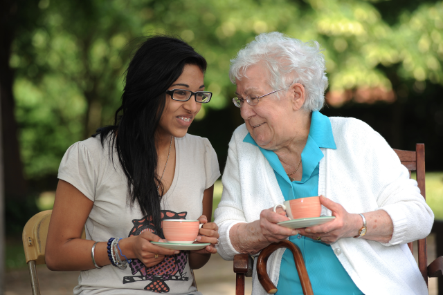 Young female and elderly female enjoying a cup of tea together