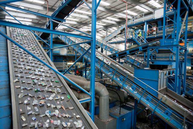 Wide angle view of a conveyor belt in a plastics recycling facility carrying plastic  waste to be recycled