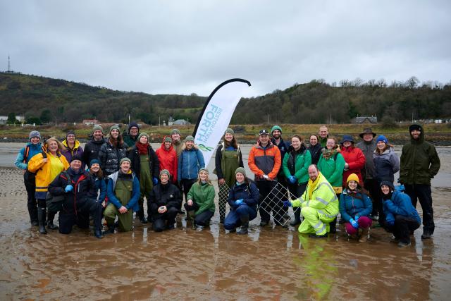 Group of volunteers stood for a group photo on the beach