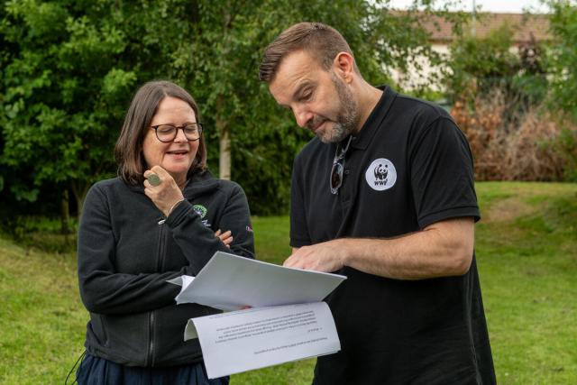 A WWF employee going over plans with a teacher in an outside space