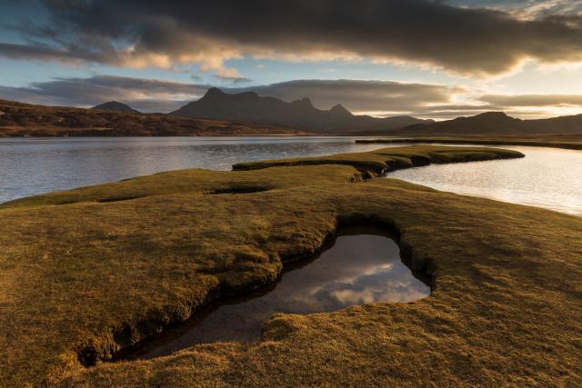 Saltmarsh exposed by low tide at sunset with view to Ben Loyal, Kyle of Tongue, Sutherland, Scotland