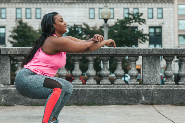 Woman completing squats in city setting