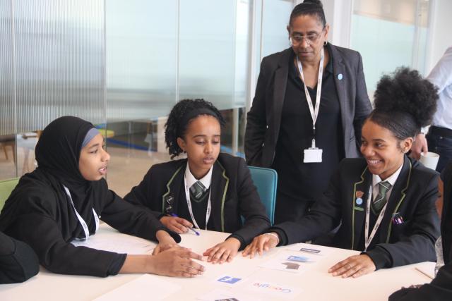 Three school pupils with their teacher, looking at their work