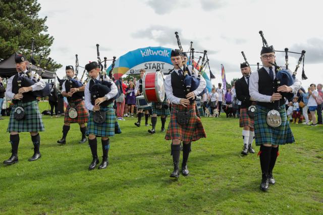 Photo of four men wearing kilts and playing bagpipes