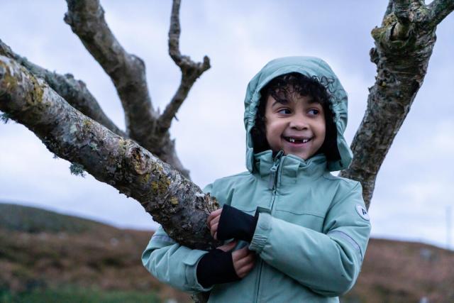 Alexander Thompson Byer son in a tree with a blue jacket on