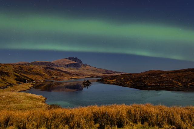 Green hues dancing across the night sky, over the Isle of Skye. The Old Man of Storr can be seen in the distance.