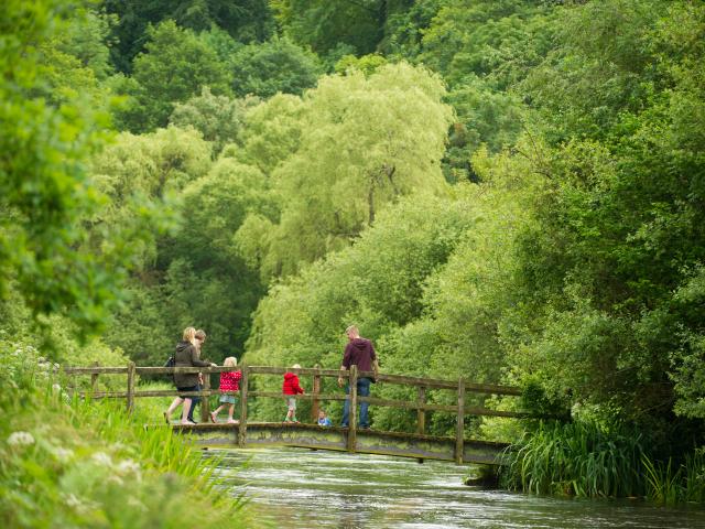 A family cross a bridge, River Itchen, Hampshire, UK
