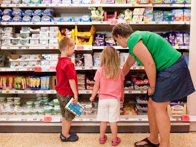 Family supermarket shopping. A mother looks at spreads with her children.