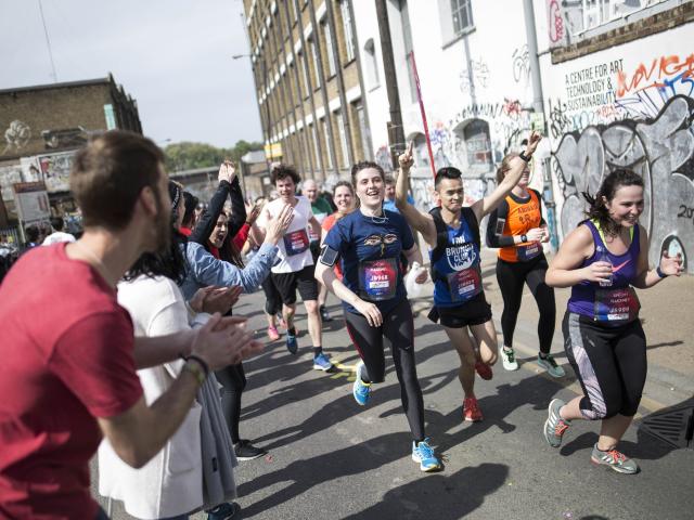 Runners are being cheered on as they go past a street in Hackney with graffitis