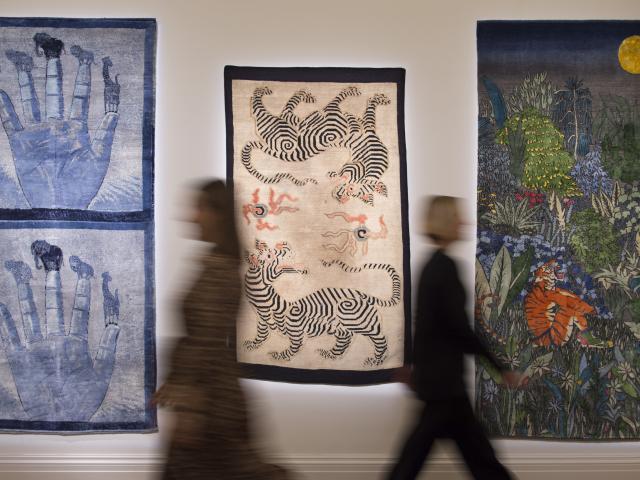 Blurred people in motion in front of three artworks in a gallery