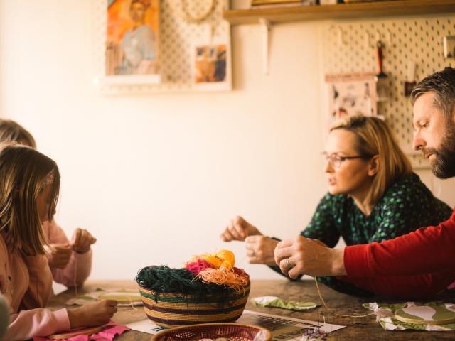 A community textile workshop supported by a WWF Cymru grant. The image shows two parents and two children sitting across from each other.