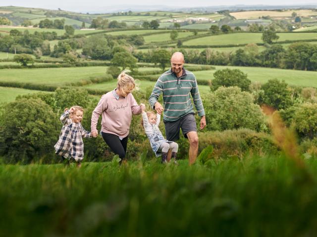 The family at Rest Farm, both parents and two children, walk through the field.