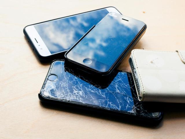 Four unused or broken mobile phones in pile 