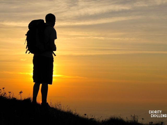 Hiker looking out at the sunrise on a mountain.