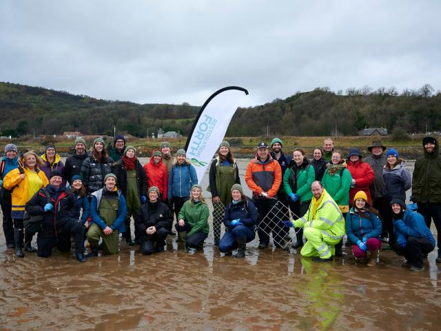 Group of volunteers stood for a group photo on the beach