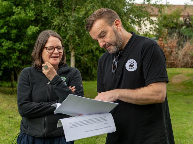 A WWF employee going over plans with a teacher in an outside space