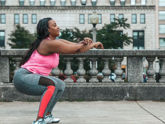 Woman completing squats in city setting