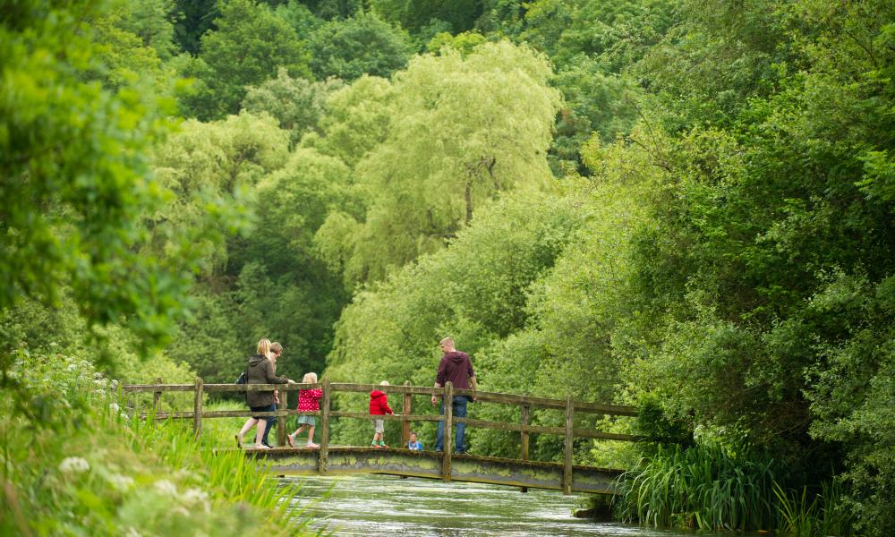 A family cross a bridge, River Itchen, Hampshire, UK
