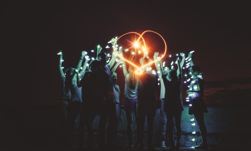 People holding fairy lights up in the dark