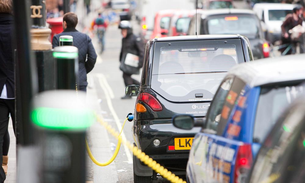 A row of electric vehicles at recharging stations on the street in Berkeley Square, London, UK.