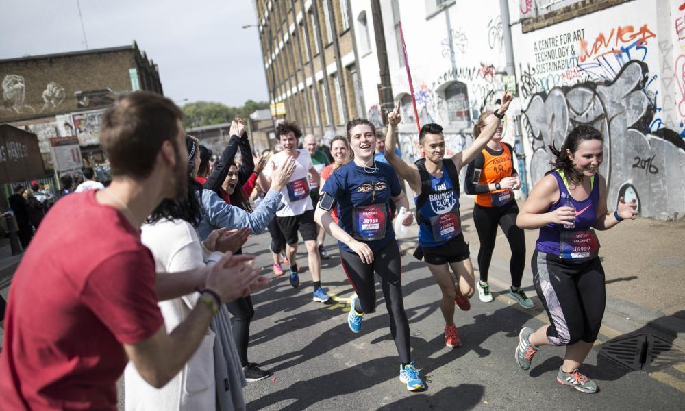 Runners are being cheered on as they go past a street in Hackney with graffitis